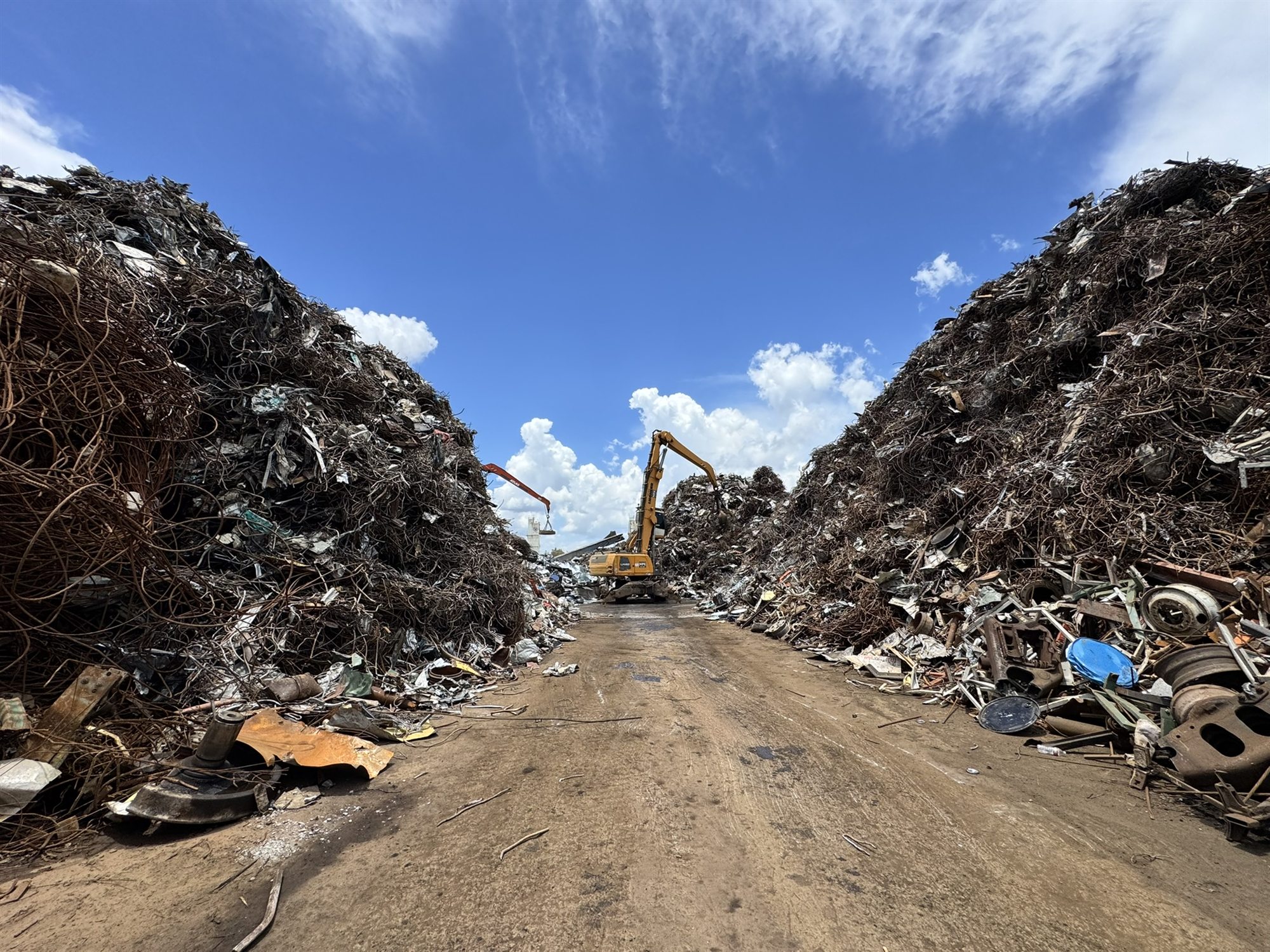 Mountains of ferrous scrap being worked by an excavator at the Gold Star Metals Houston yard